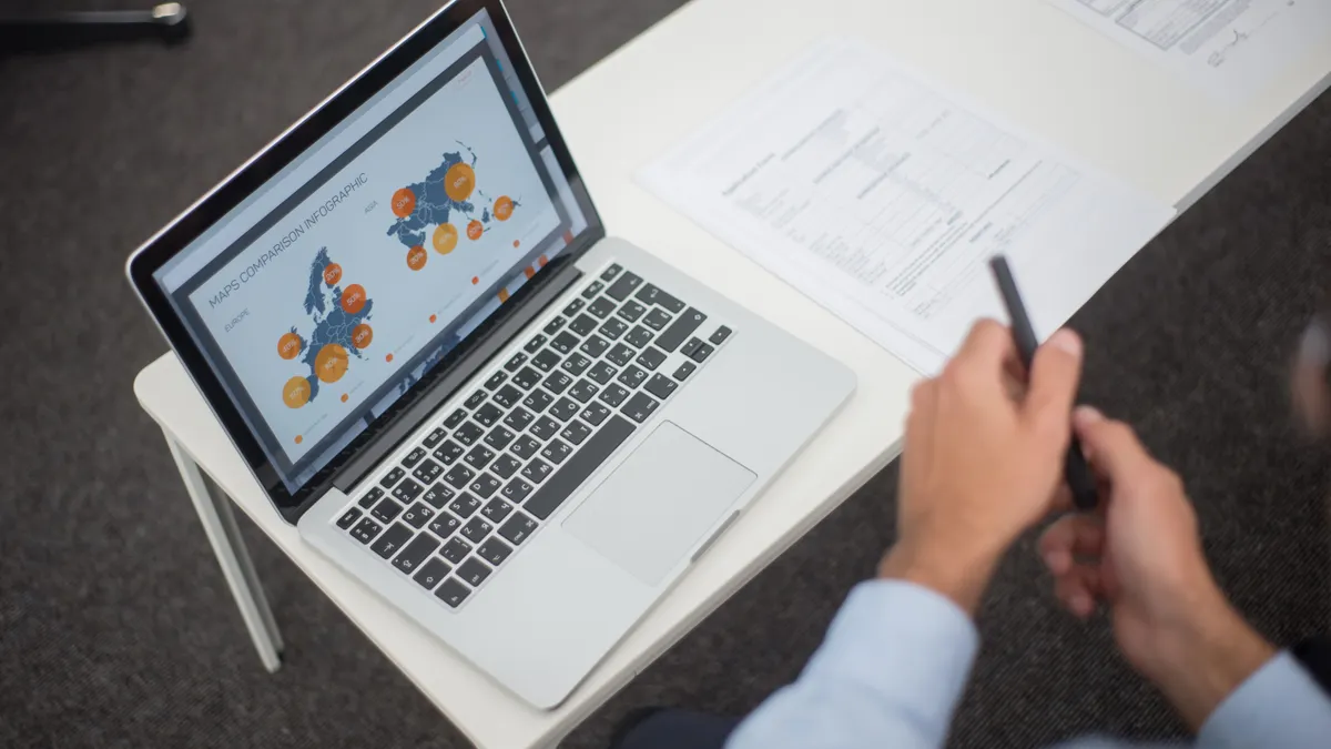 Laptop with clustered node graphics and charts on screen